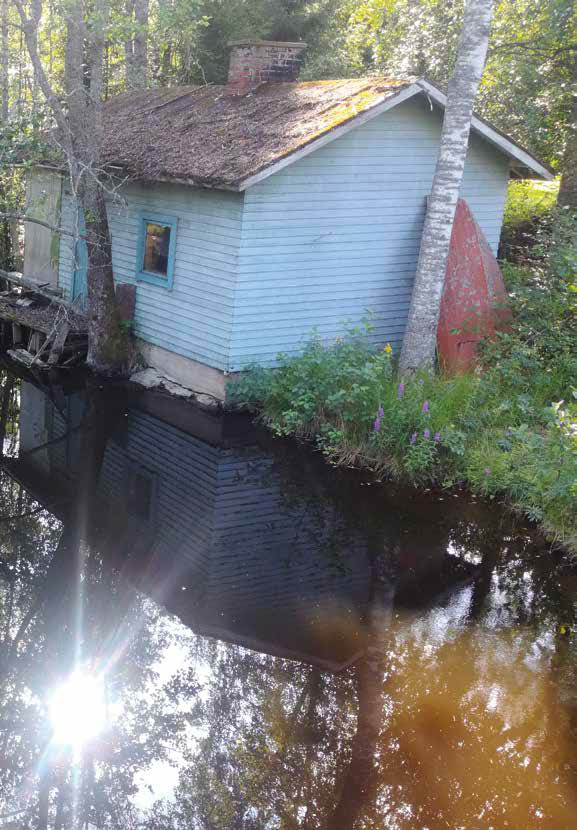 A small blue cottage by a river.