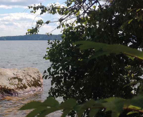 A big rock in the water near the shore.